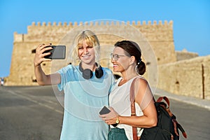 Mom and teenage daughter taking selfie near historic fortress