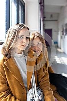 Mom and teenage daughter in yellow clothes relax by the window .Parents and teens. Family look