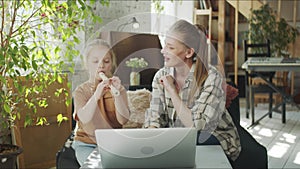 Mom tells the child how best to play the flute. They watch lessons on a laptop