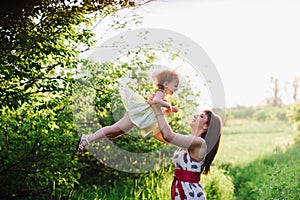 Mom throws daughter plays in sunset ligt