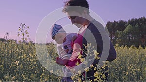 Mom tickles baby in rapeseed field slow motion