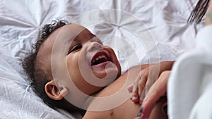 Mom tickles her adorable biracial baby boy who laughs out loud.