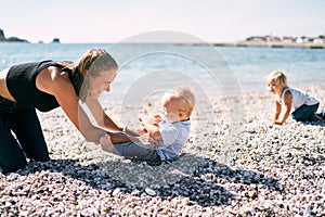 Mom tickles a little boy on a pebble beach