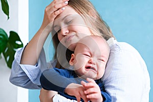 Mom tired trying to calm her crying baby. Newborn tantrum child on mother hands. Family life, motherhood