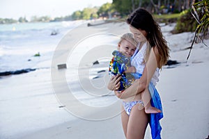 Mom and toddler boy, happily hugging on the ocean shore, relaxing
