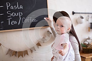 Mom and Toddler Daughter playing menu planning write to blackboard and chalk,