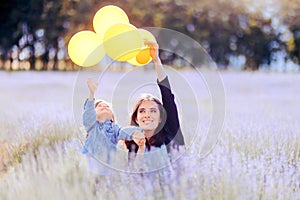 Mom and Toddler Daughter Playing with Yellow Balloons in a Lavender Field