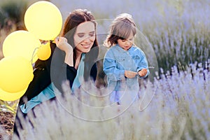 Mom and Toddler Daughter Playing with Yellow Balloons in a Lavender Field