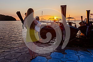 Mom with a toddler enjoys the sunrise standing on the pantone pier. Rear view, from the back