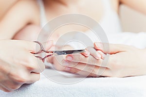 Mom tonsured nails on the hands newborn using nail scissors