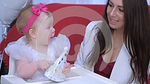 Mom is trying to puts on party cap on her baby daughter at her first birthday.