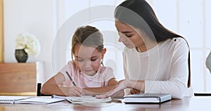 Mom tutor teach help child daughter learn writing doing homework