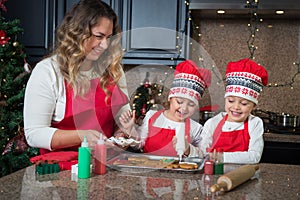 Mom and twin girls in red making Christmas cookies