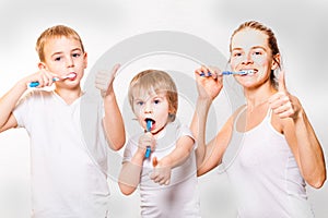 Mom and two blond boys brush their teeth