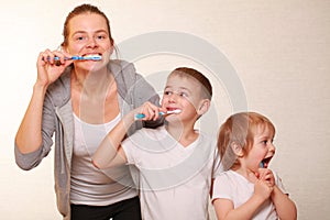 Mom and two blond boys brush their teeth