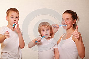 Mom and two blond boys brush their teeth