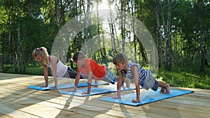 Mom and two boys performing yoga poses outdoors