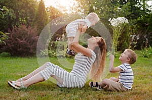 Mom, two children rest on nature. Sibling rivalry. Brothers, Motherhood.