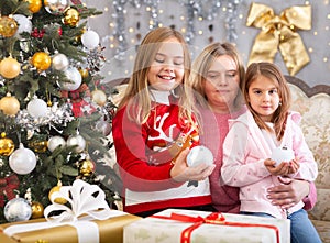 Mom with two daughters hugging in Christmas interior