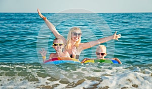 Mom and two sons are swimming in the sea. Children in bright inflatable circles. Summer vacations.