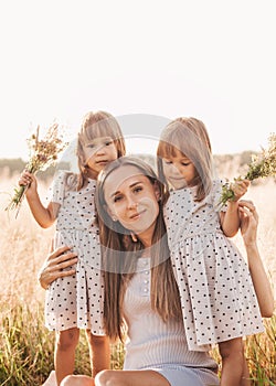 Mom with two twin girls playing in nature in the summer