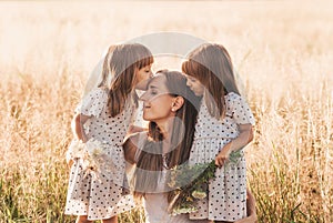 Mom with two twin girls playing in nature in the summer