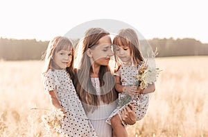 Mom with two twin girls playing in nature in the summer