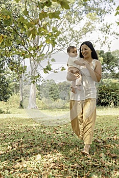 Mom walking with her baby in her arms enjoying a sunny day in the park