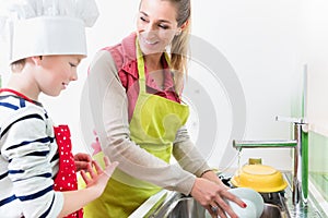 Mom washing-up the crockery, son helping