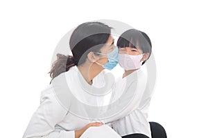 Mom wearing a mask is kissing her daughter wearing a mask