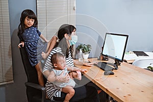 Mom wearing masks carrying her baby working home