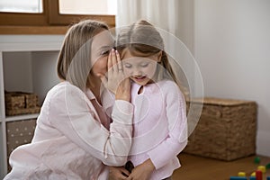 Mom whispers on daughters ear her secret