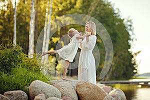 Mom in a white dress with her daughter sitting on large rocks on