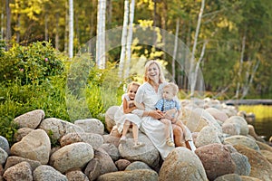 Mom in a white dress with her son and daughter sitting on large
