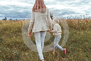 Mom woman in autumn in park holds child s hand, little boy 3-5 years old son, nature relax on a walk, in spring in field