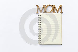 Mom wooden letter on Blank yellow lined note book isolate on white background