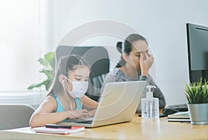 Mom working at home with her child on the table while writing an report. woman working from home, while in quarantine isolation