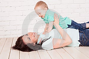 Mom and young boy son lying on the wooden floor play