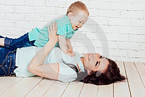 Mom and young boy son lying on the wooden floor play