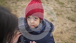 Mom zips up her son`s jacket on the street