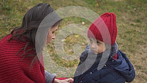 Mom zips up her son`s jacket on the street