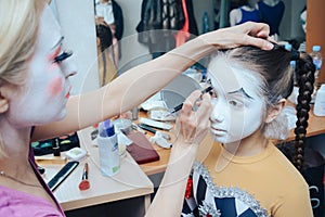 the moment of applying clown makeup to a little girl.