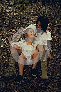 moment of complicity between a mother and her daughter sitting in nature. Autumn season