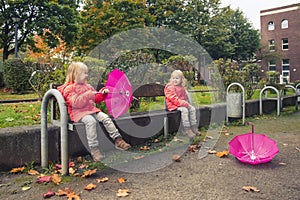 Moment of happiness! Happy little girls with umbrellas on a sunny autumn day after the rain, children in bright jackets in the par