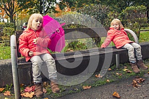 Moment of happiness! Happy little girls with umbrellas on a sunny autumn day after the rain, children in bright jackets in the par