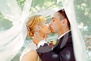 A moment before a kiss of newlyweds standing under a veil