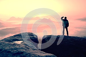 Moment of loneliness. Man on the rock empires and watch over the misty and foggy morning valley to Sun