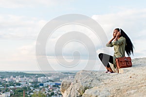 Moment of relaxing outdoor. Gorgeous african american hipster woman with smartphone and headphones listening to music