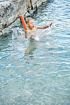 Moment of small boy diving into water while jumping in sea