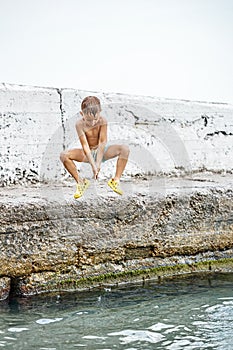 Moment of small boy jumping from pier into sea water